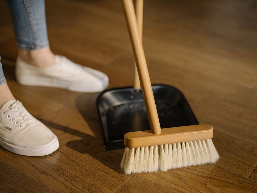 Bodenpflege mit Besen und Kehrschaufel auf Parkett